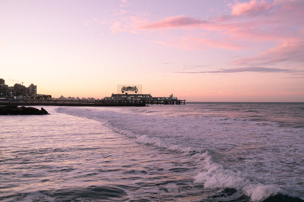 services-04 Beautiful sunset view at Mar del Plata beach, Argentina with ocean waves and pier silhouette.