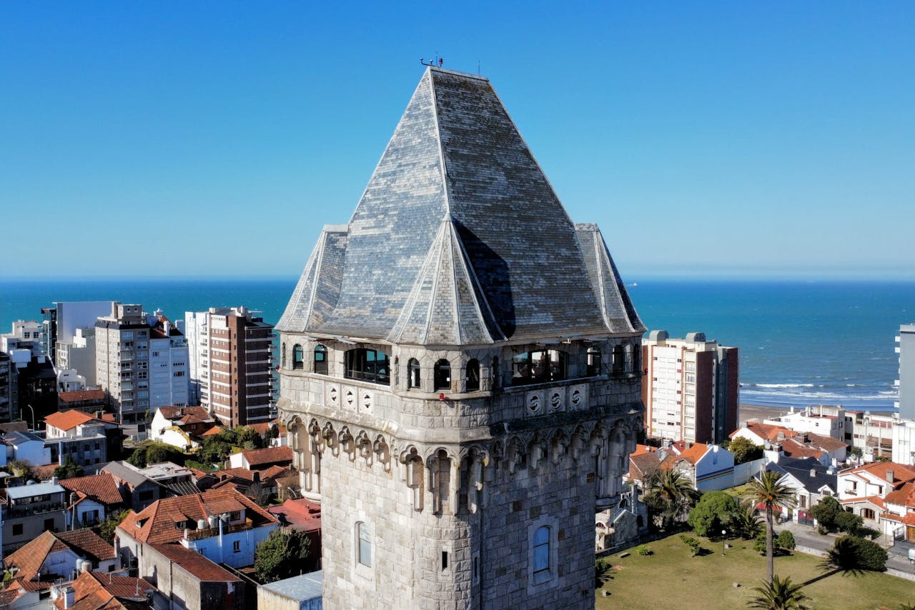 A stunning aerial shot of Tanque Tower by the coast in Mar del Plata, showcasing urban architecture and the sea.